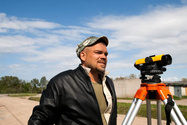 Theodolite on a tripod with construction worker — Stock Photo, Image