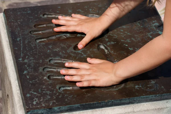 Manos de niños en impresiones de manos metálicas — Foto de Stock