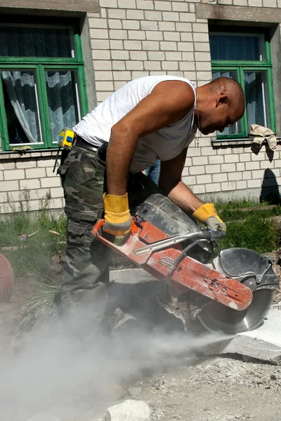 Trabalhador com serra industrial cortando um bloco de concreto — Fotografia de Stock