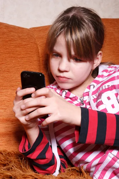 一个非常严重的女孩手机上玩游戏 — 图库照片