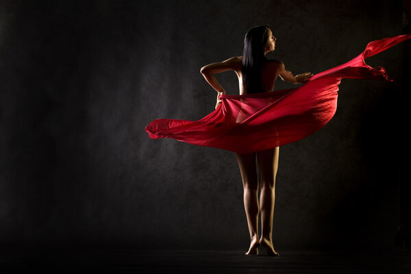 Nude model in studio dancing with red cloth