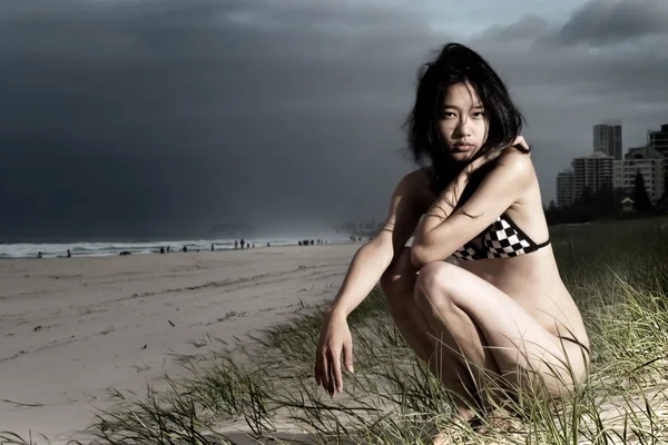 Бикини девушка на пляже с темными облаками — стоковое фото