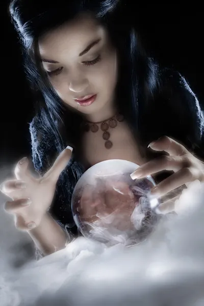 En spåkvinnan blickar in i hennes kristallkula Stockbild