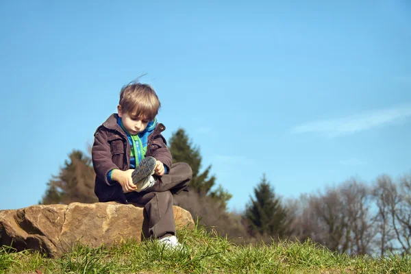 A little boy sitting on a rock. — Stock Photo, Image