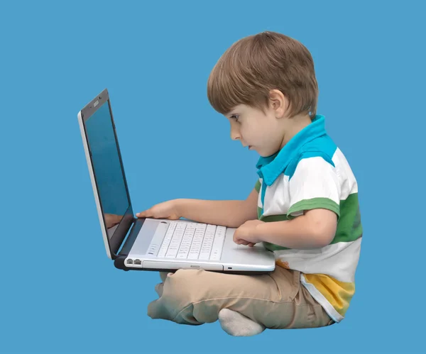 Jongen met laptop geïsoleerd op een blauwe achtergrond — Stockfoto