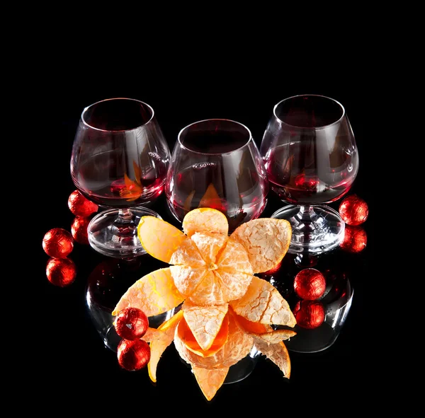 Vasos de vino, mandarina y chocolate sobre fondo negro — Foto de Stock