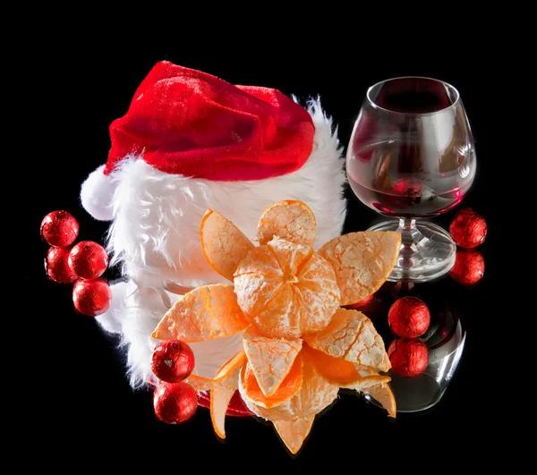 Gläser Wein, Mandarine und Schokolade und Weihnachtsmann-Hut auf schwarzem Bac — Stockfoto