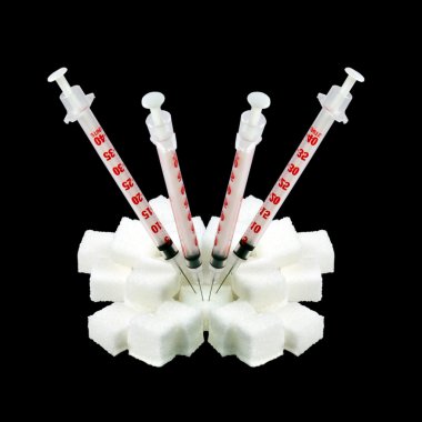 Insulin syringes stuck into the lump sugar. isolated on a black background clipart