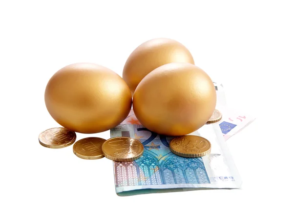 Huevos dorados con billetes de dinero sobre fondo blanco — Foto de Stock