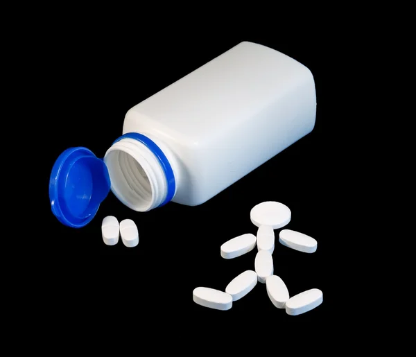 Um recipiente para comprimidos e um homem construído com comprimidos ao lado dele. . — Fotografia de Stock
