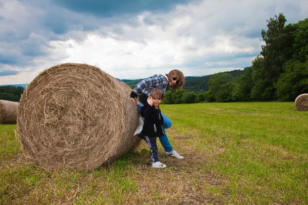 Una ragazza e un ragazzo spingono un fascio rotondo di paglia . — Foto Stock