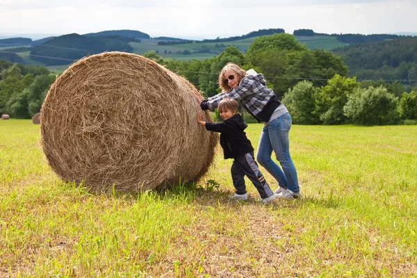 Ein Mädchen und ein Junge schieben ein rundes Bündel Stroh. — Stockfoto