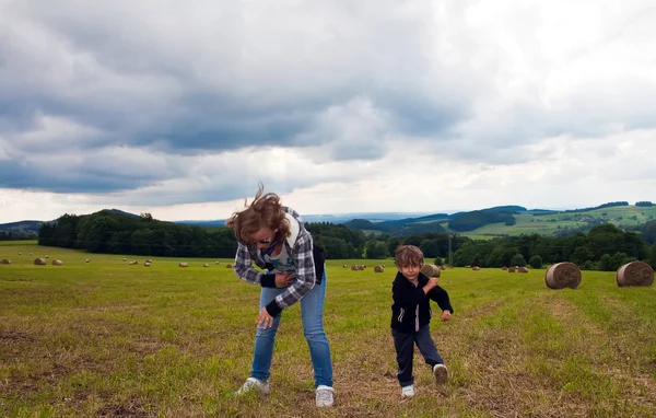 Ragazza e ragazzo che ballano sul campo falciato in un fascio di paglia . — Foto Stock