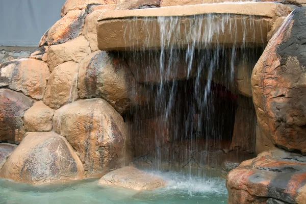 An artificial grotto with a waterfall. — Stock Photo, Image