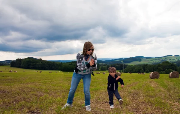 Chica y niño bailando en el campo segado en una gavilla de paja . — Foto de Stock
