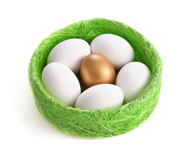 Белые и золотые яйца в гнезде из травы на белом фоне — стоковое фото