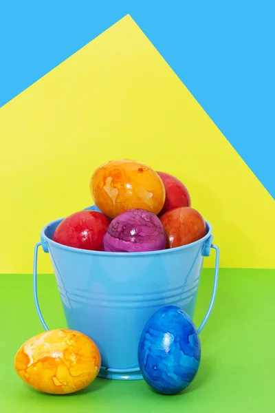 在彩色背景上，存储桶中的复活节彩蛋 — 图库照片