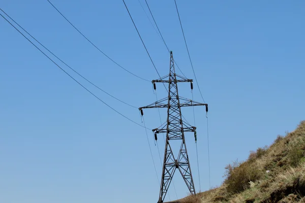 Široký úhel pohledu pylonu elektřiny proti modré oblohy jasno — Stock fotografie