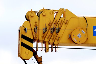 Yellow industrial utillity crane hook against electric pole and blue sky clipart