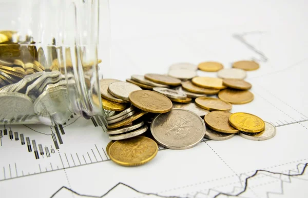 Монеты, пролитые из банки на бизнес-фоне — стоковое фото