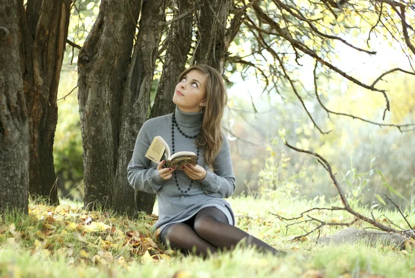 stock image The beautiful girl sits under a tree with the book