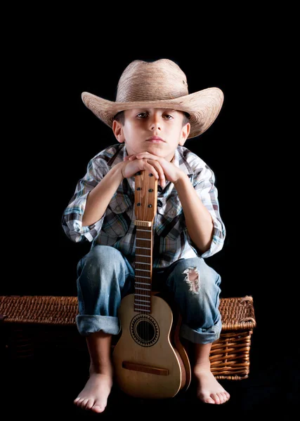 Chłopak z gitarą na czarnym tle w kapeluszu — Zdjęcie stockowe