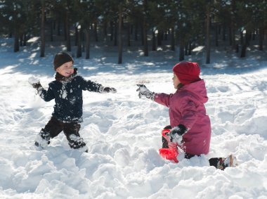 Boy and girl playing snowballs clipart