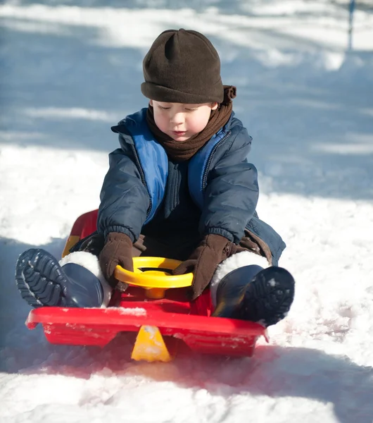 stock image The boy sits on a sled