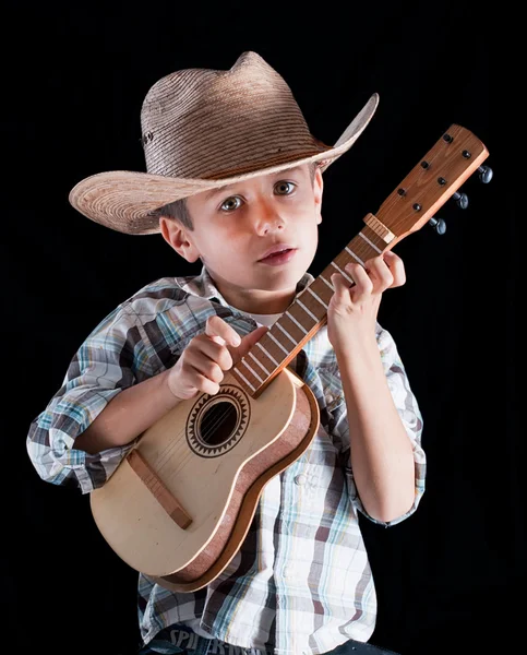 Мальчик в шляпе с гитарой на черном фоне — стоковое фото