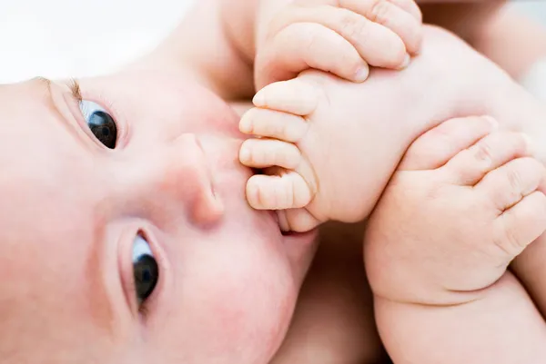 Ein kleiner Junge lutscht Zehen an ihren Füßen — Stockfoto