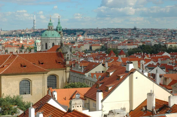 Kostel svatého Mikuláše a červenými střechami v Praze — Stock fotografie