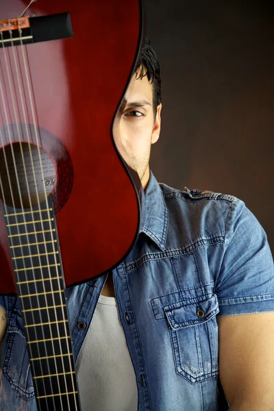 Male model hiding behind guitar — Stock Photo, Image