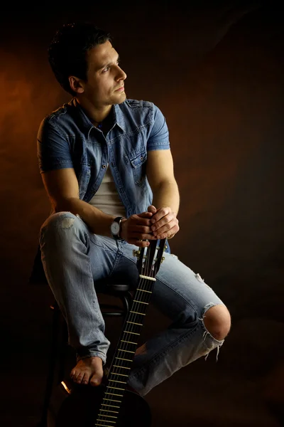 Serious male model with guitar thinking — Stock Photo, Image