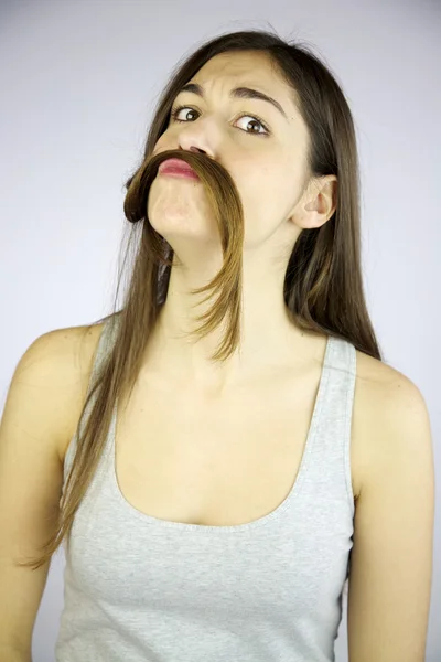 Menina engraçada fazendo bigode com seu cabelo muito longo — Fotografia de Stock
