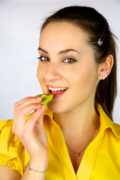 Beautiful girl eating fresh kiwi smiling happy — Stock Photo, Image