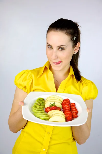 Beautiful girl showing happy a plate full of fresh fruit — Stock Photo, Image