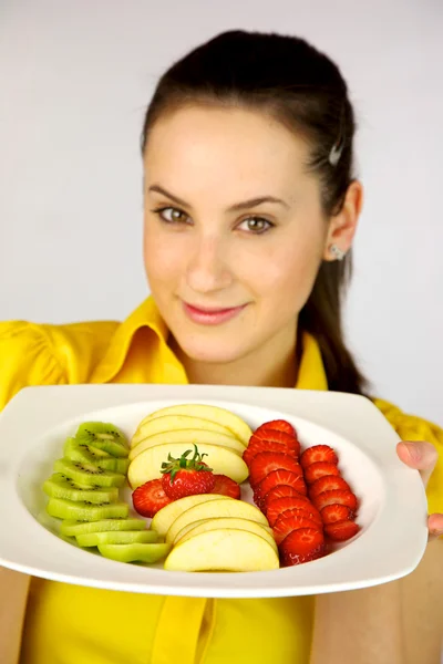 Morena modelo femenino mostrando fruta fresca en un plato —  Fotos de Stock