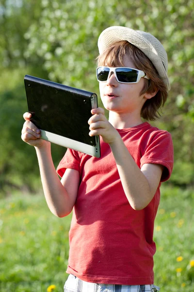 De blonde jongen speelt in de tablet pc — Stockfoto