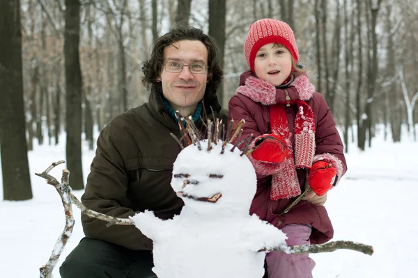 Papá y su hija al lado del muñeco de nieve — Foto de Stock