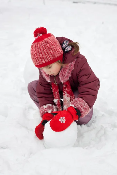 Маленькая девочка делает снеговика — стоковое фото