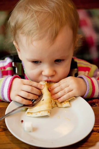 Baby eats the delicious pancakes — Stock Photo, Image