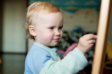 Baby drawing chalk on a blackboard clipart