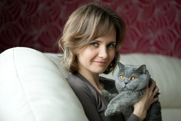 Mujer bastante joven jugando con un gato gris — Foto de Stock