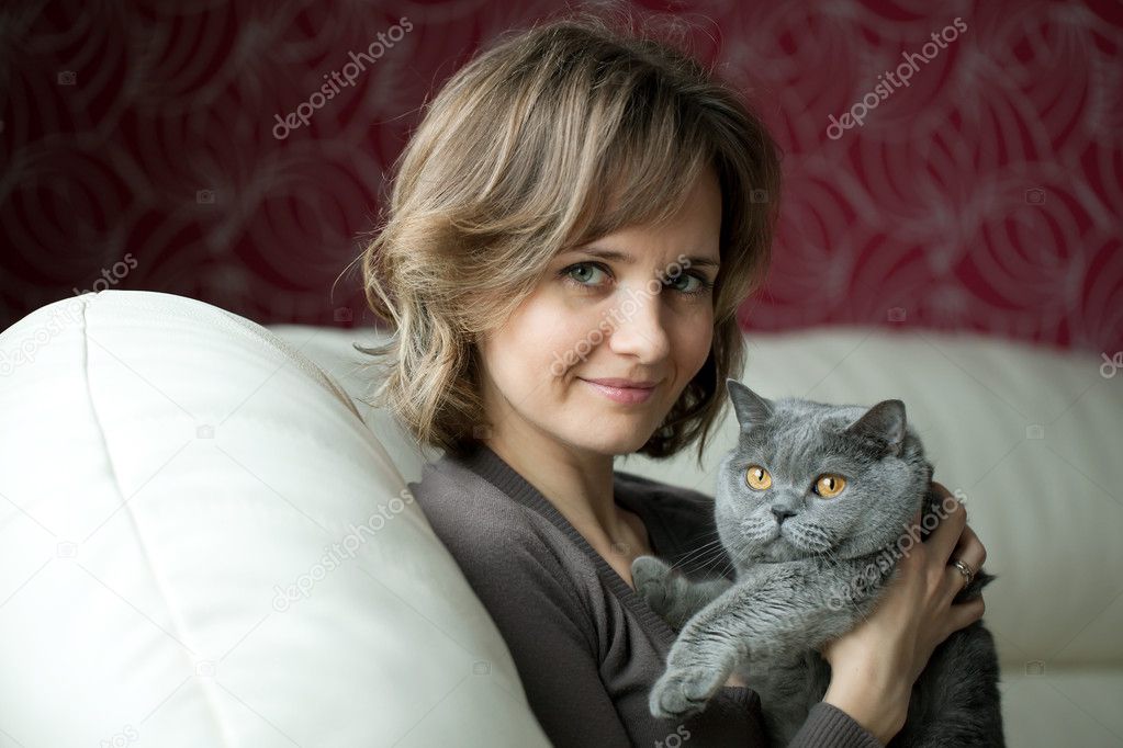Pretty young woman playing with a gray cat