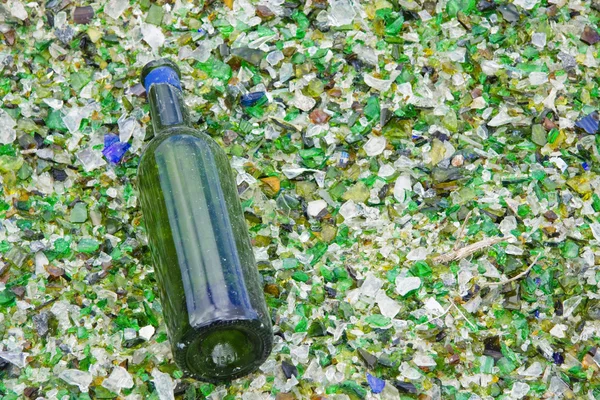 Бутылка на разбитом стекле — стоковое фото