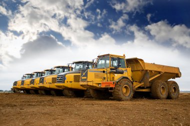 Row of yellow heavy tipper lorries clipart