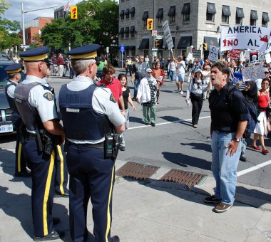 Protester hollers at 2 Royal Canadian Mounted Police clipart