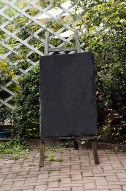Standing blackboard agaist wooden fence clipart