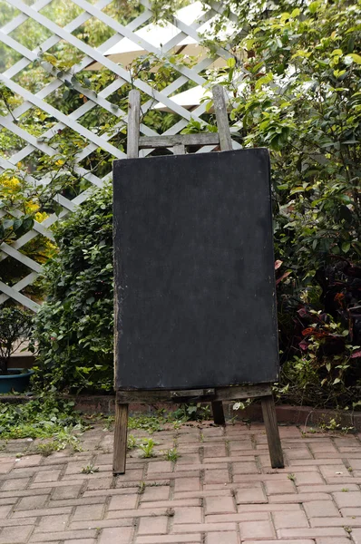 Standing blackboard agaist wooden fence — Stock Photo, Image