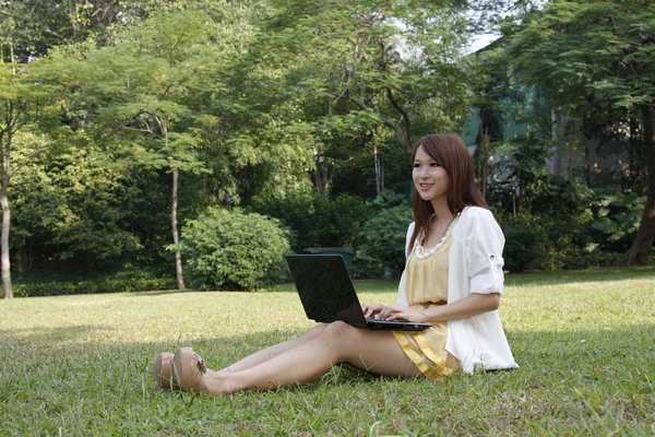 Asian girl using laptop on grass — Stock Photo, Image